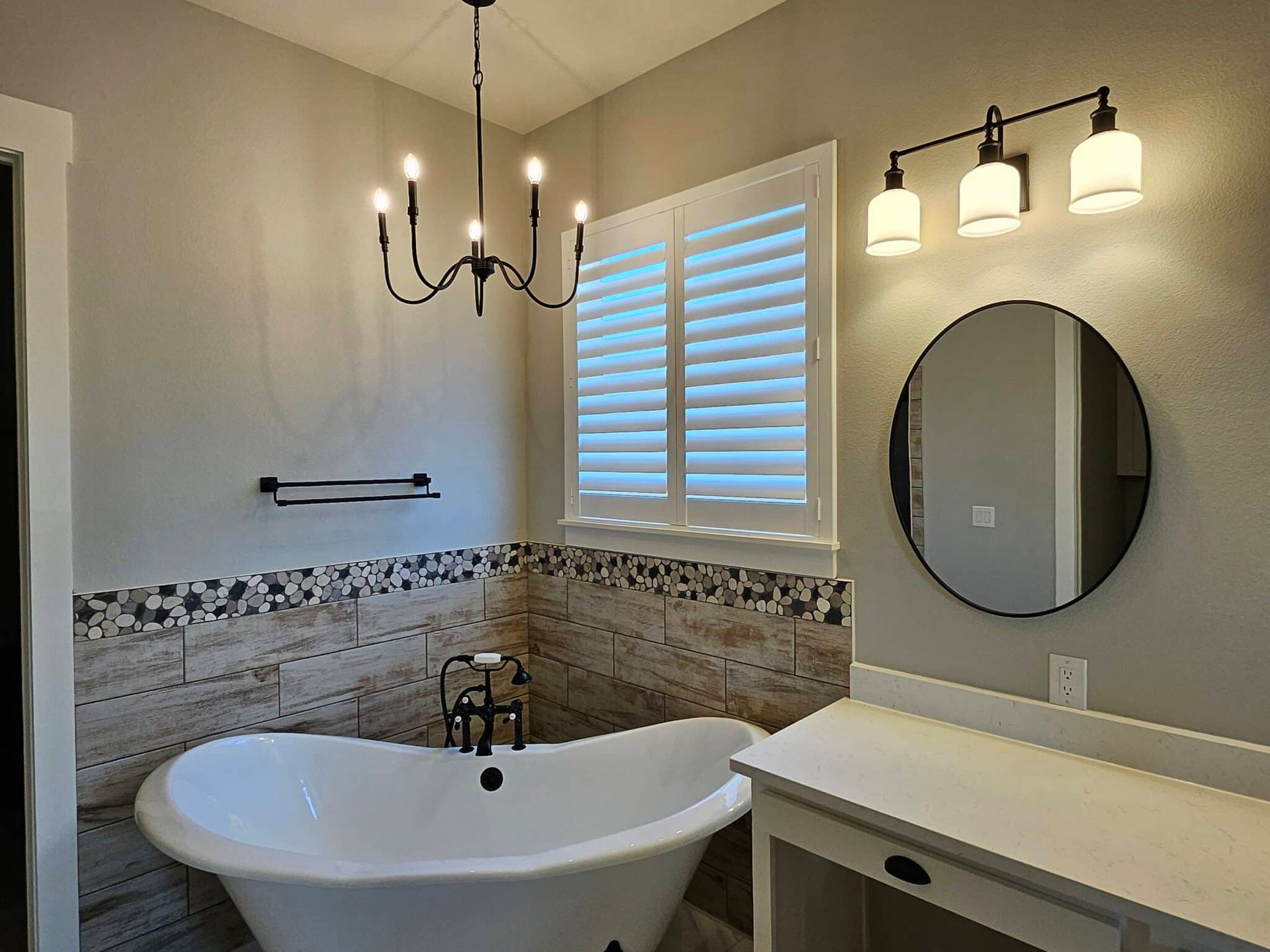 Bathroom with a clawfoot tub, shutters, vanity, and black light fixtures.