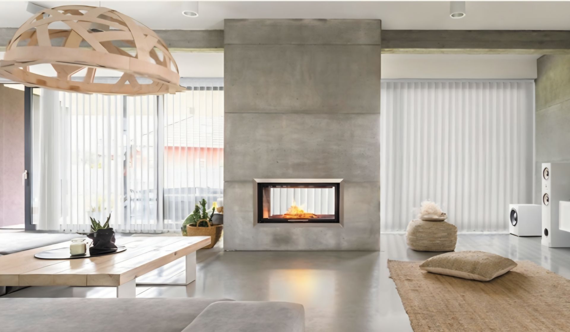 Modern living room with fireplace, wooden lamp, concrete walls, and light-colored furniture.