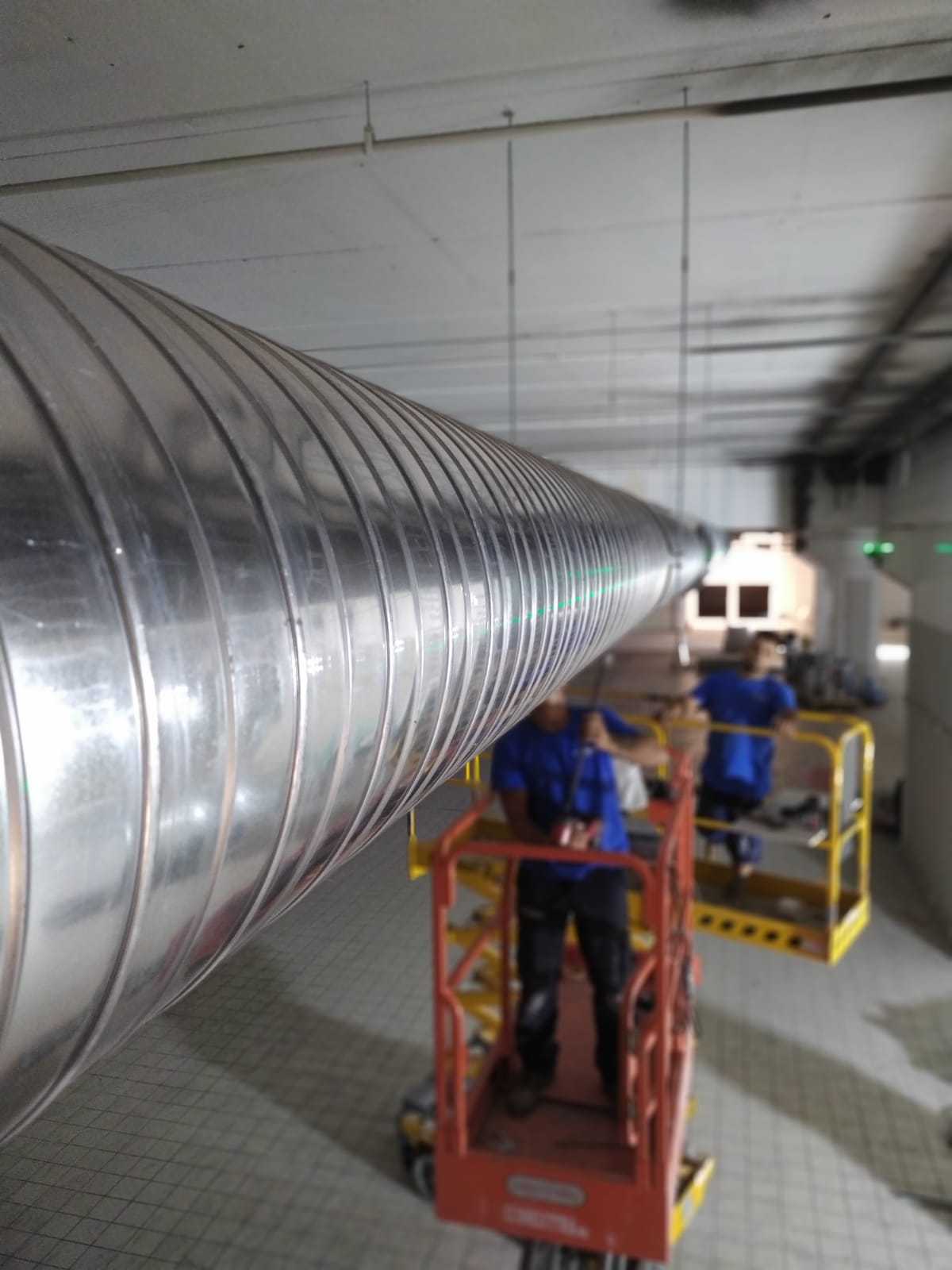 Corridoio in un magazzino con alti scaffali metallici pieni di scatole e contenitori blu.