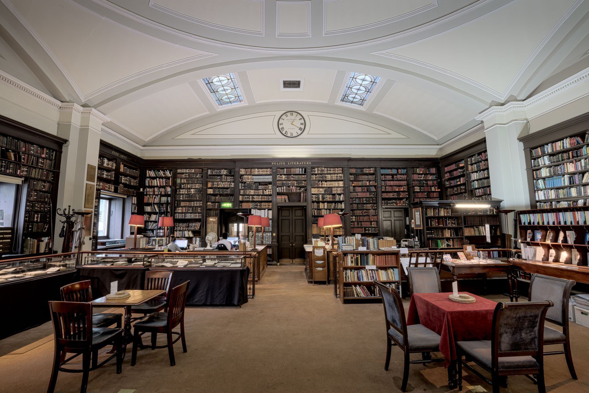 Historic library reading room with tall bookshelves, wooden tables, and a curved white ceiling
