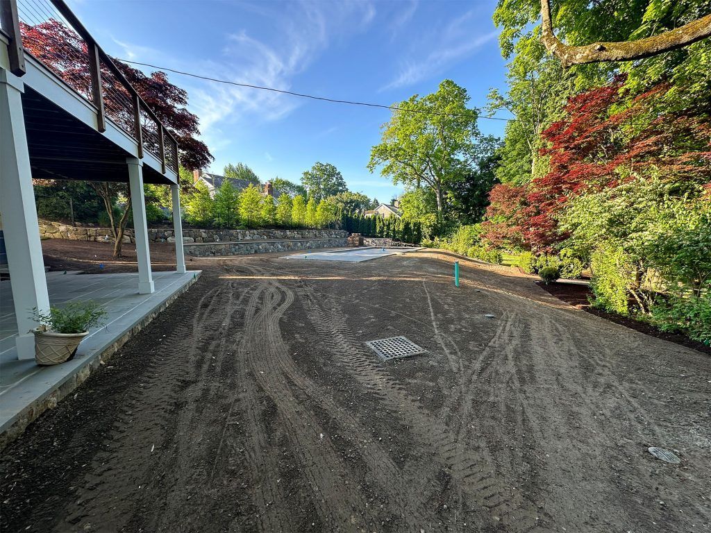 Gravel driveway beside a white porch, lined with colorful trees under a bright blue sky