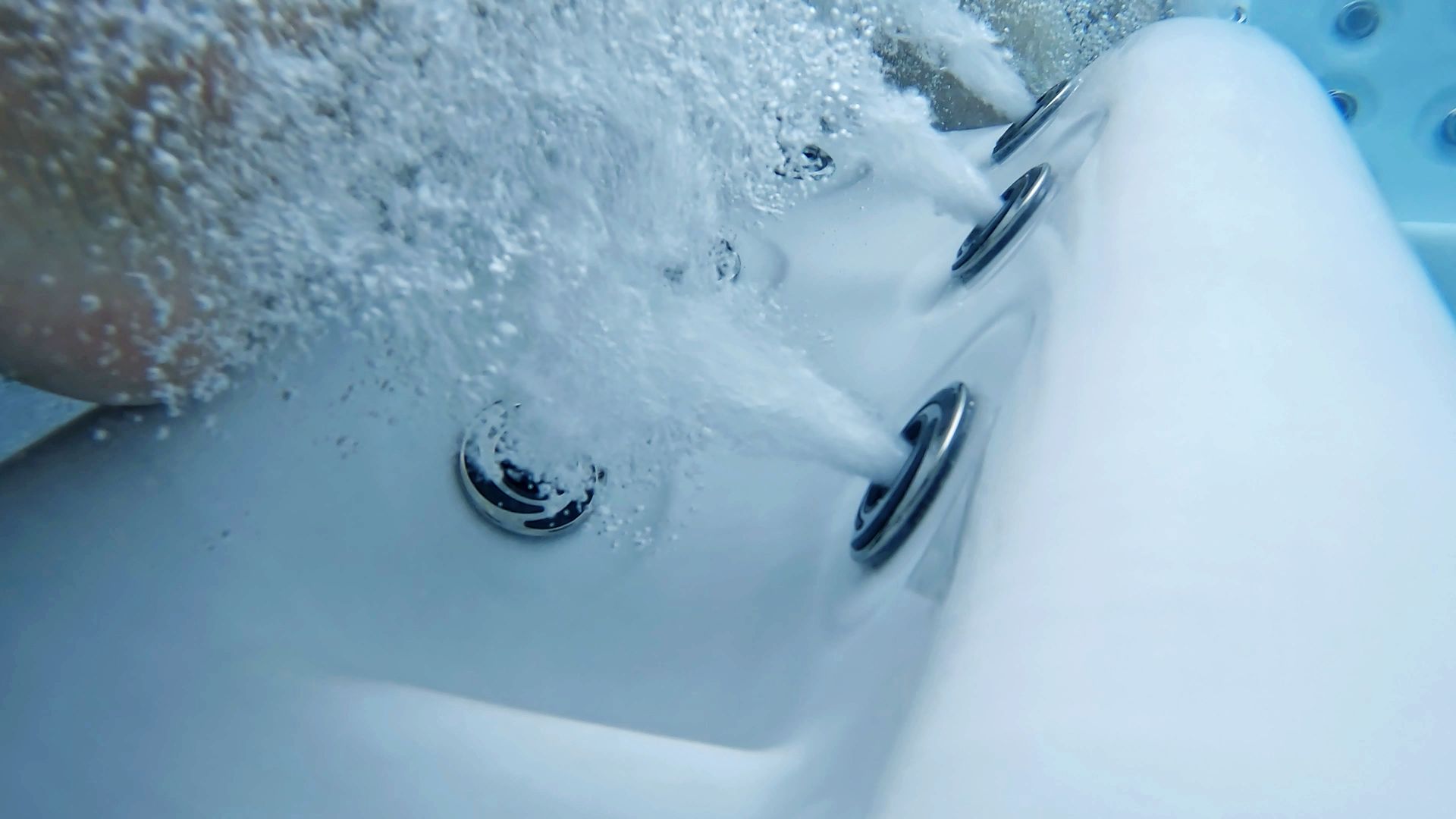 Snow-covered hot tub with water jets bubbling and partially visible metal jets on the side