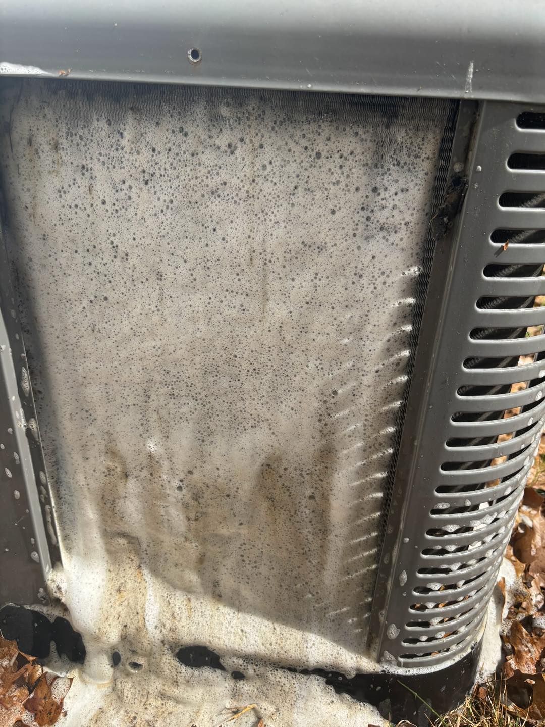 Air conditioner coil covered in white cleaning foam.