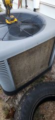 AC unit exterior with debris on the fins and a tire in the foreground.