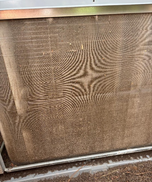 Dusty tan HVAC filter with visible dirt buildup in a metal frame