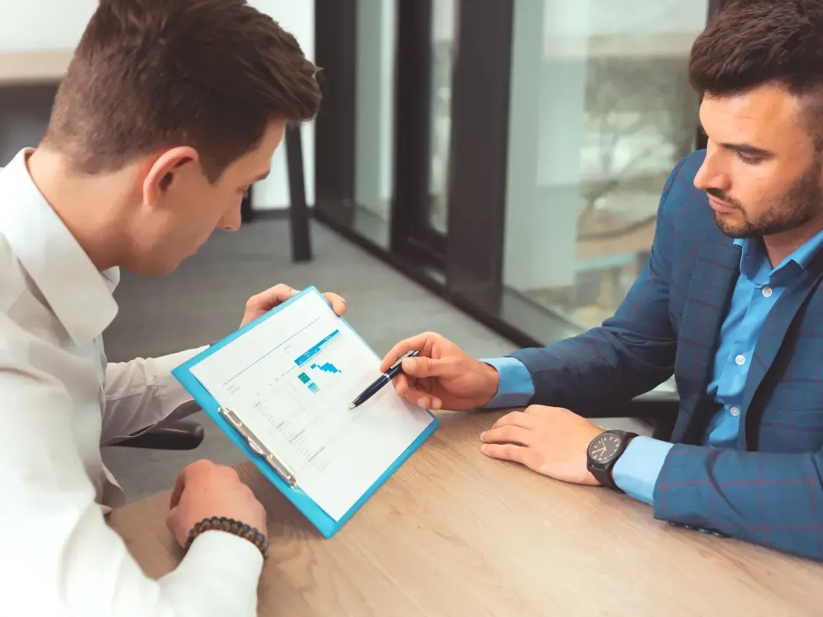 An insurance accountant points to a document to provide key accounting insights to a colleague.