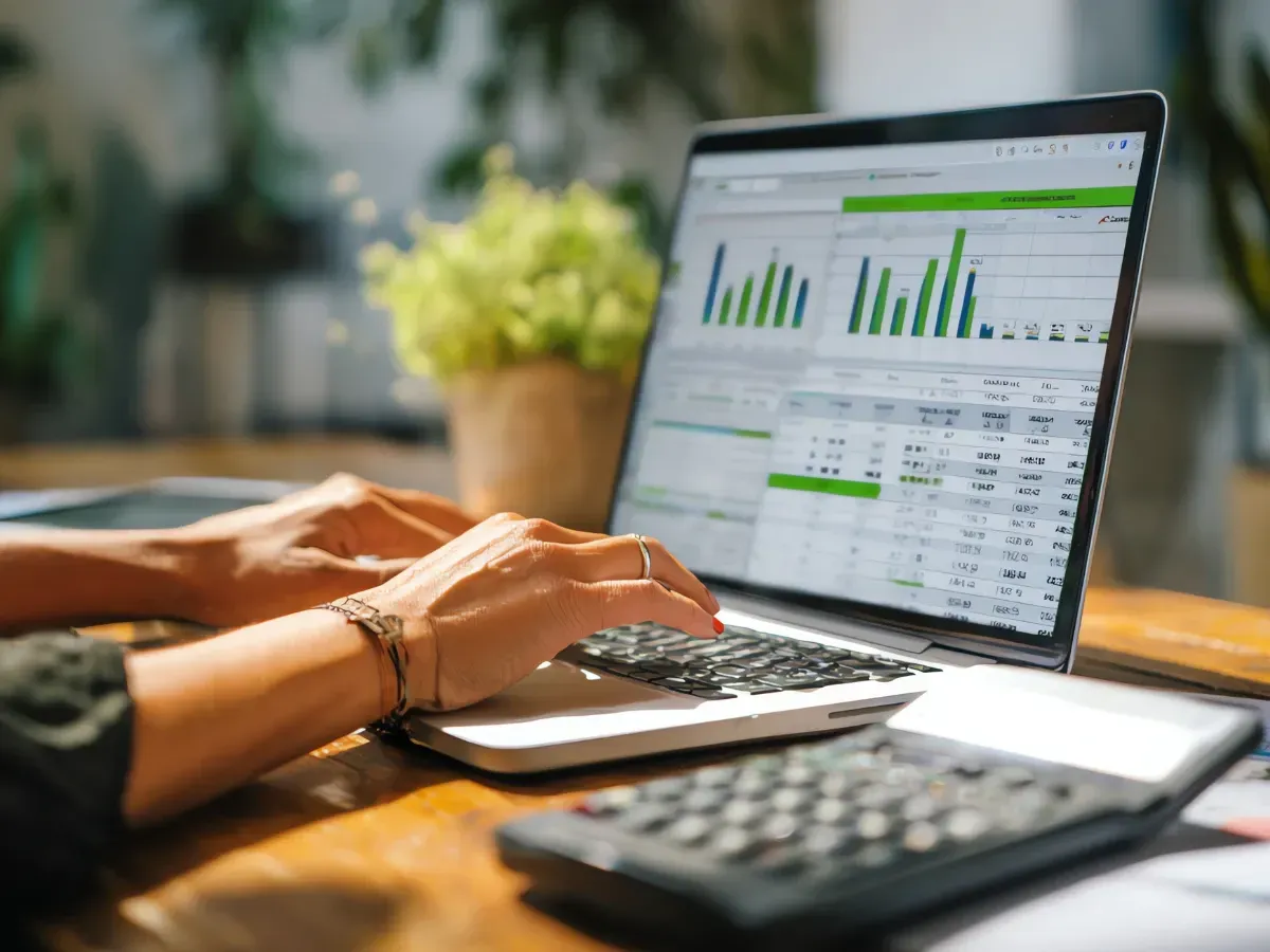 An insurance bookkeeper working on a laptop dashboard with financial charts and reports displayed.