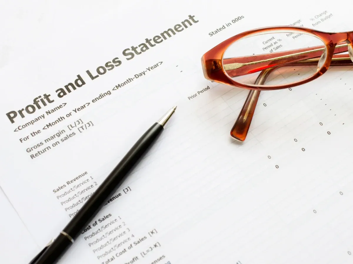 An insurance company profit and loss statement with a pen and glasses.