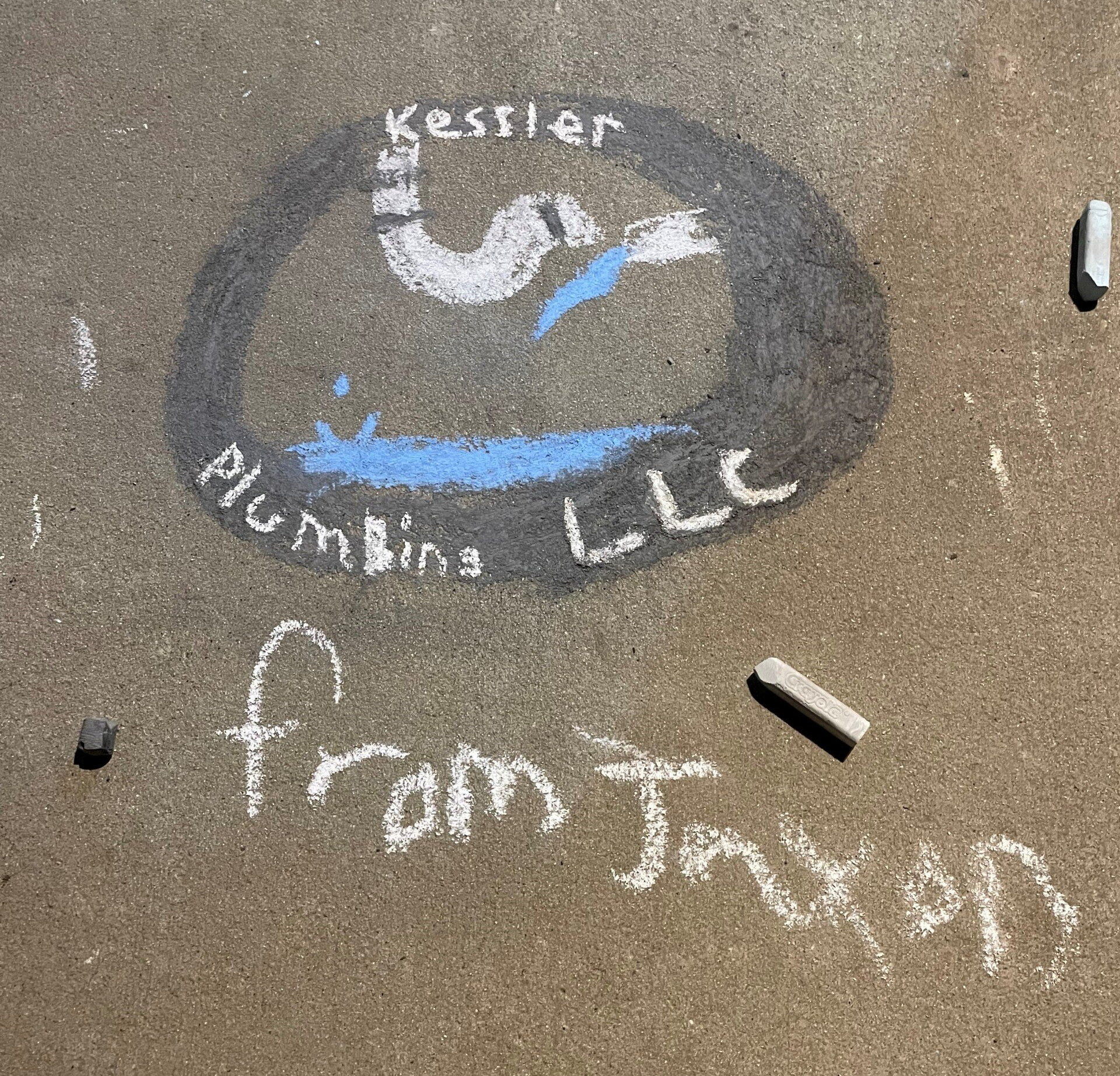 Chalk drawing on pavement of Kessler Plumbing LLC logo, with