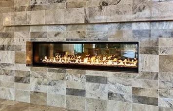 Fireplace built into stone wall, flames inside glass enclosure.