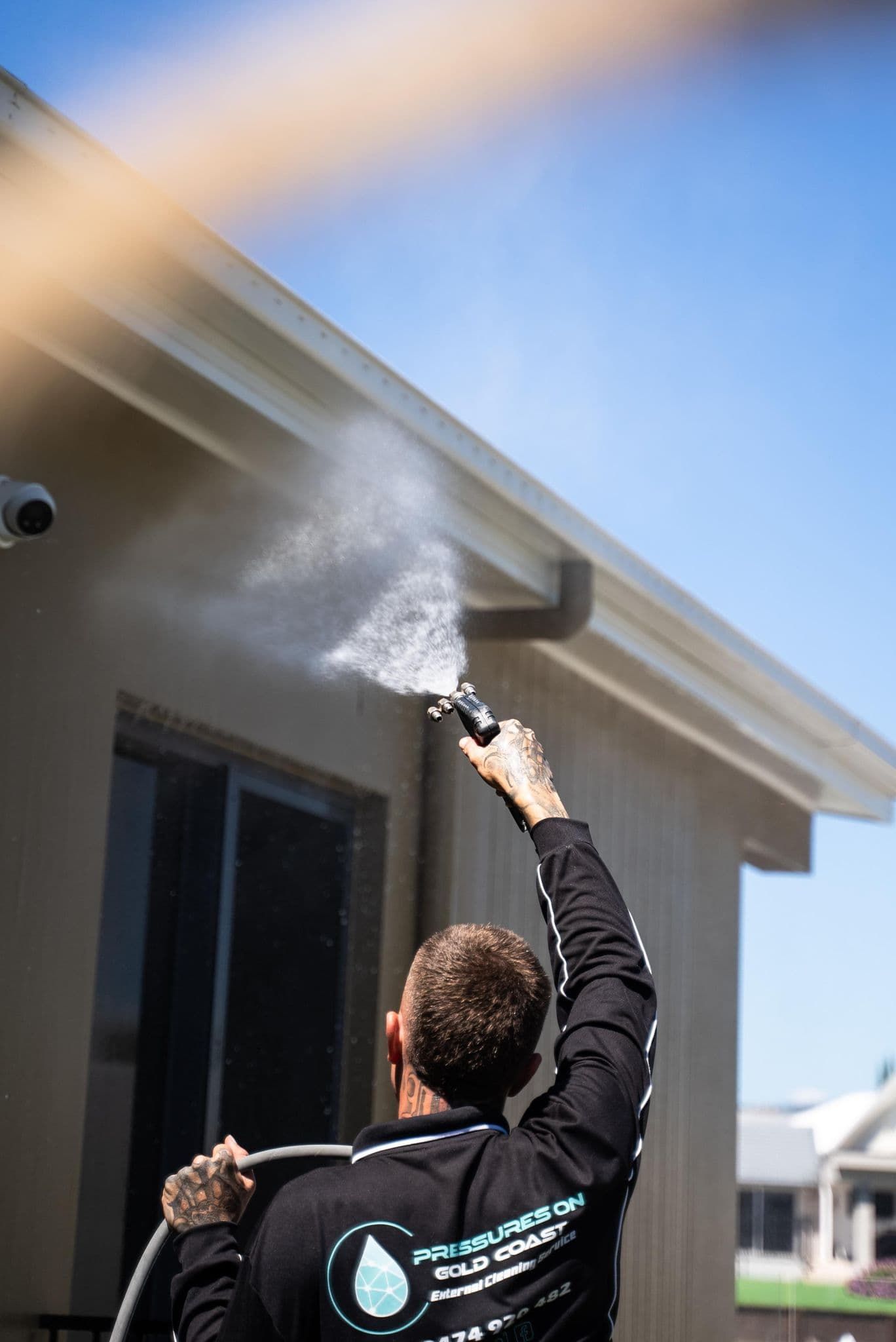 a man is spraying water on the side of a house with a hose .