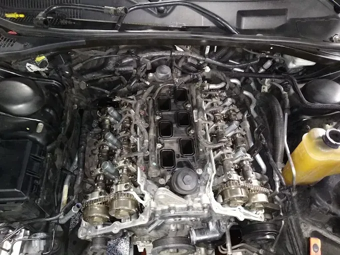 Car engine, top view. Internal components exposed; intricate wiring and metal parts.