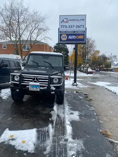 Black Mercedes-Benz G-Class SUV parked in front of Montclare Auto Care on a snowy day.
