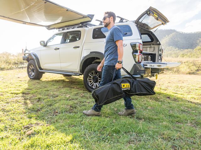 Man Carrying a Black Bag Near SUV — Lacey's TJM 4X4 Megastore in Rockhampton City, QLD