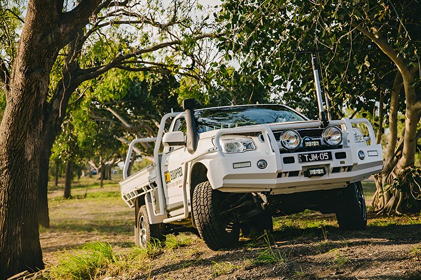 A White Truck is Parked in a Field Surrounded by Trees — Lacey's TJM 4X4 Megastore in Rockhampton City, QLD