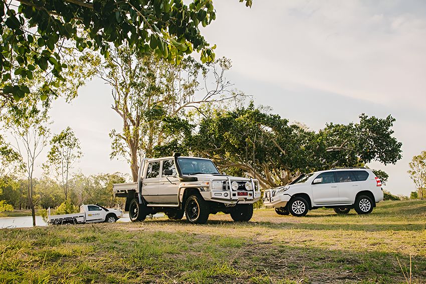 Two White Trucks Are Parked Next to Each Other in a Grassy Field — Lacey's TJM 4X4 Megastore in Rockhampton City, QLD