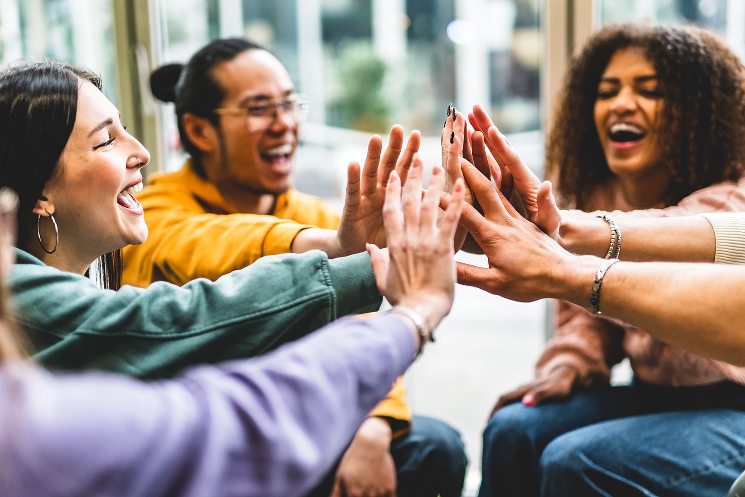 A group of people are giving each other a high five while sitting in a circle.