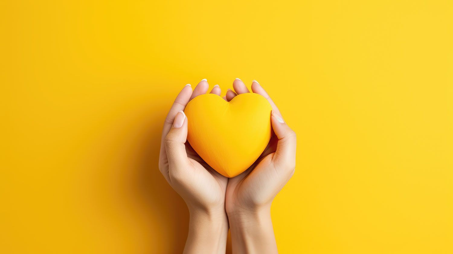 Hands holding a yellow heart against a yellow background.