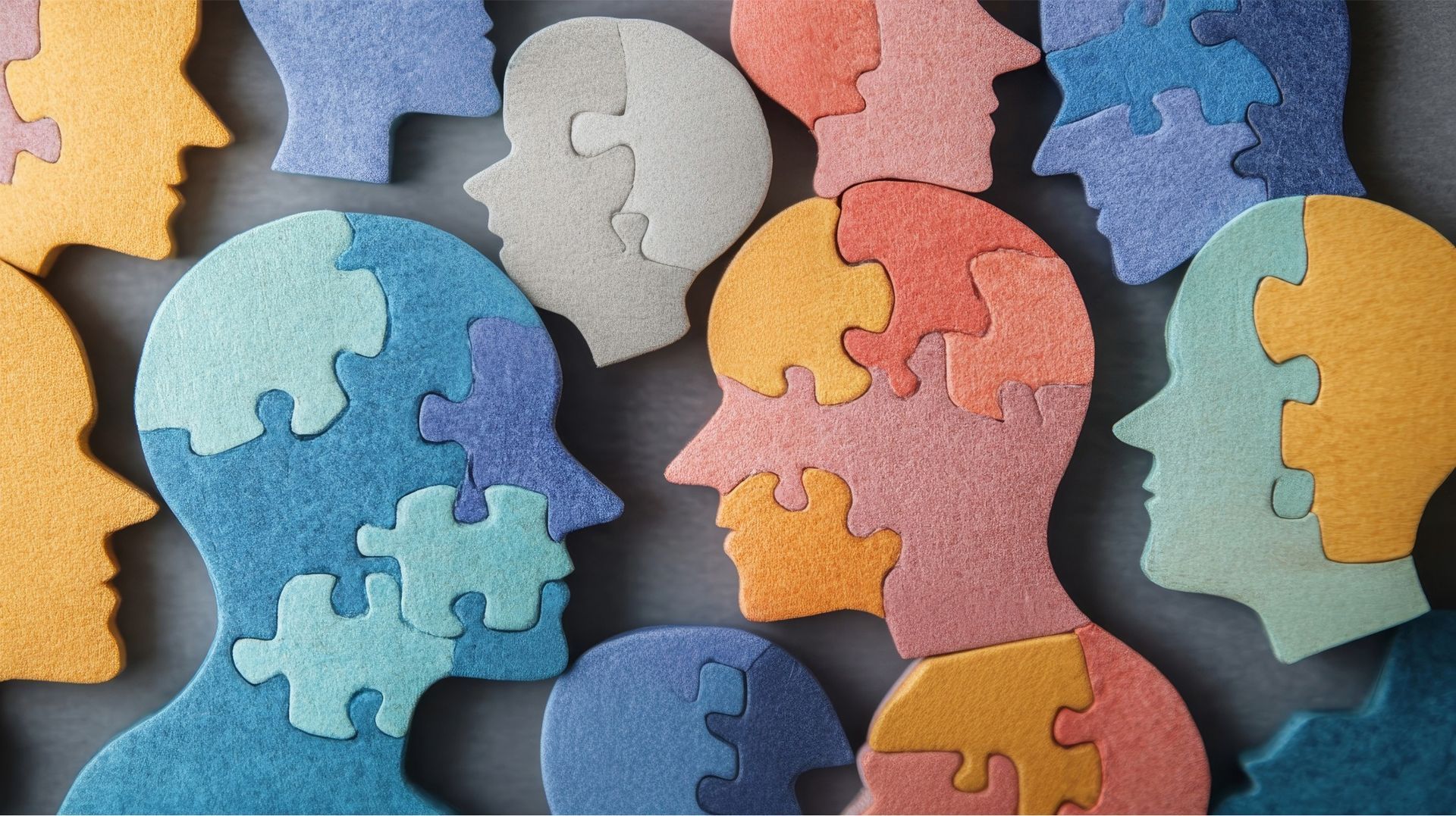 Heads made of puzzle pieces in various colors, symbolizing diverse thoughts and minds.