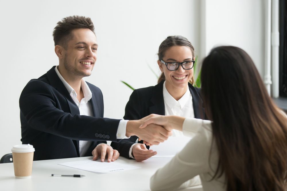A man and a woman are shaking hands during a job interview.