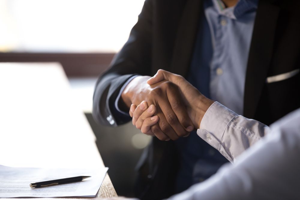 A man and a woman are shaking hands over a table.