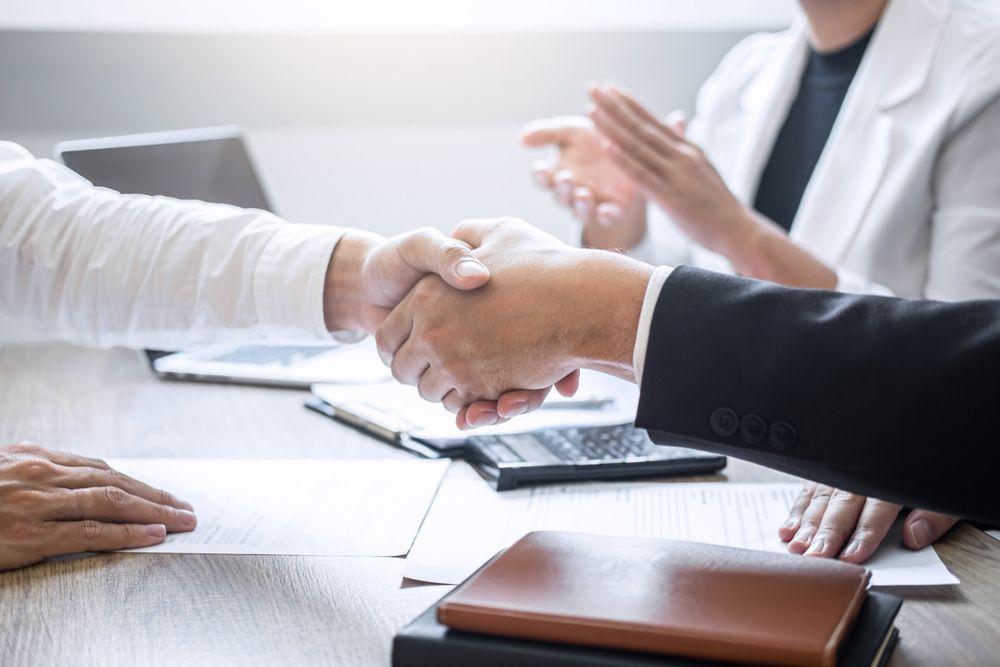 A man and a woman are shaking hands over a table.
