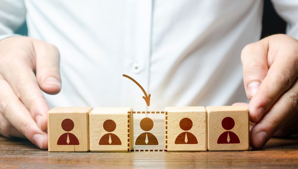 A person is holding wooden blocks with people on them.