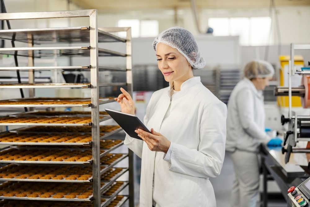 A woman is looking at a tablet in a bakery.