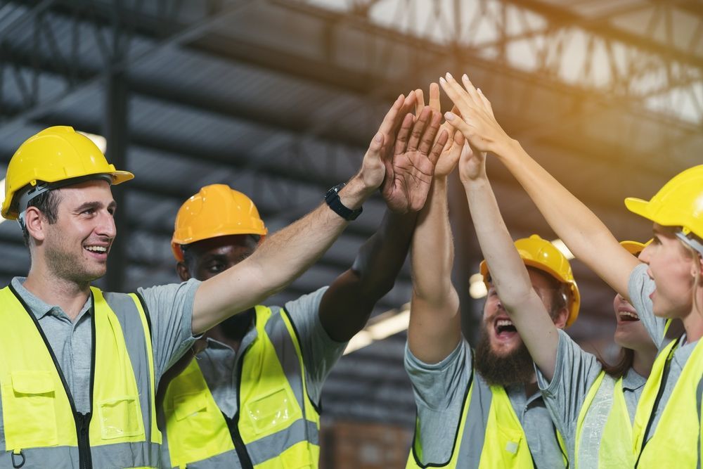 A group of construction workers are giving each other a high five.