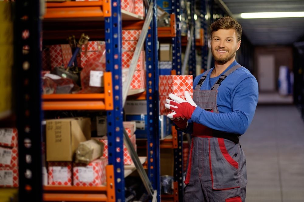 A man is holding a box in a warehouse.