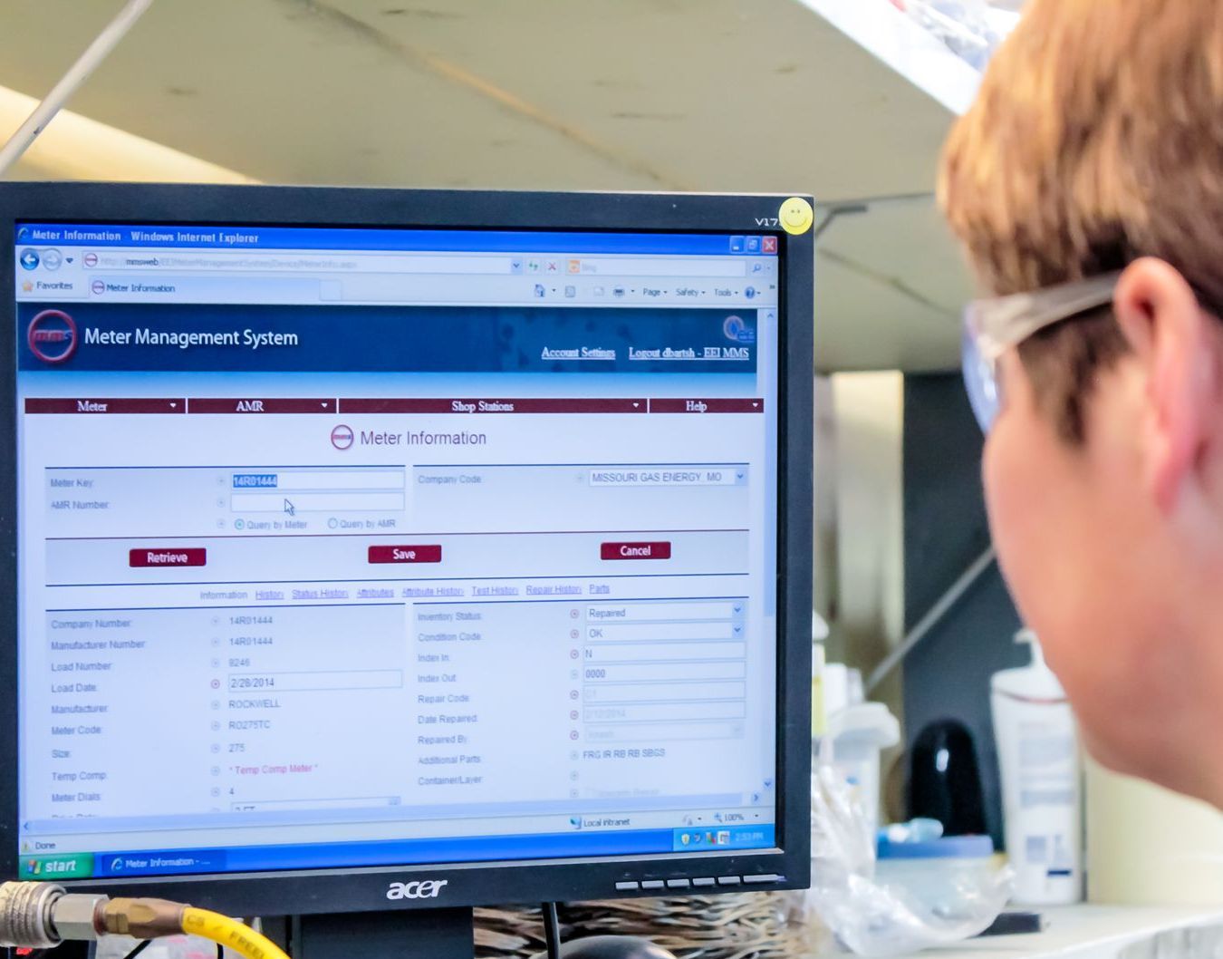 A person with glasses looks at a computer screen displaying the Meter Management System Software. The setting appears to be a lab.