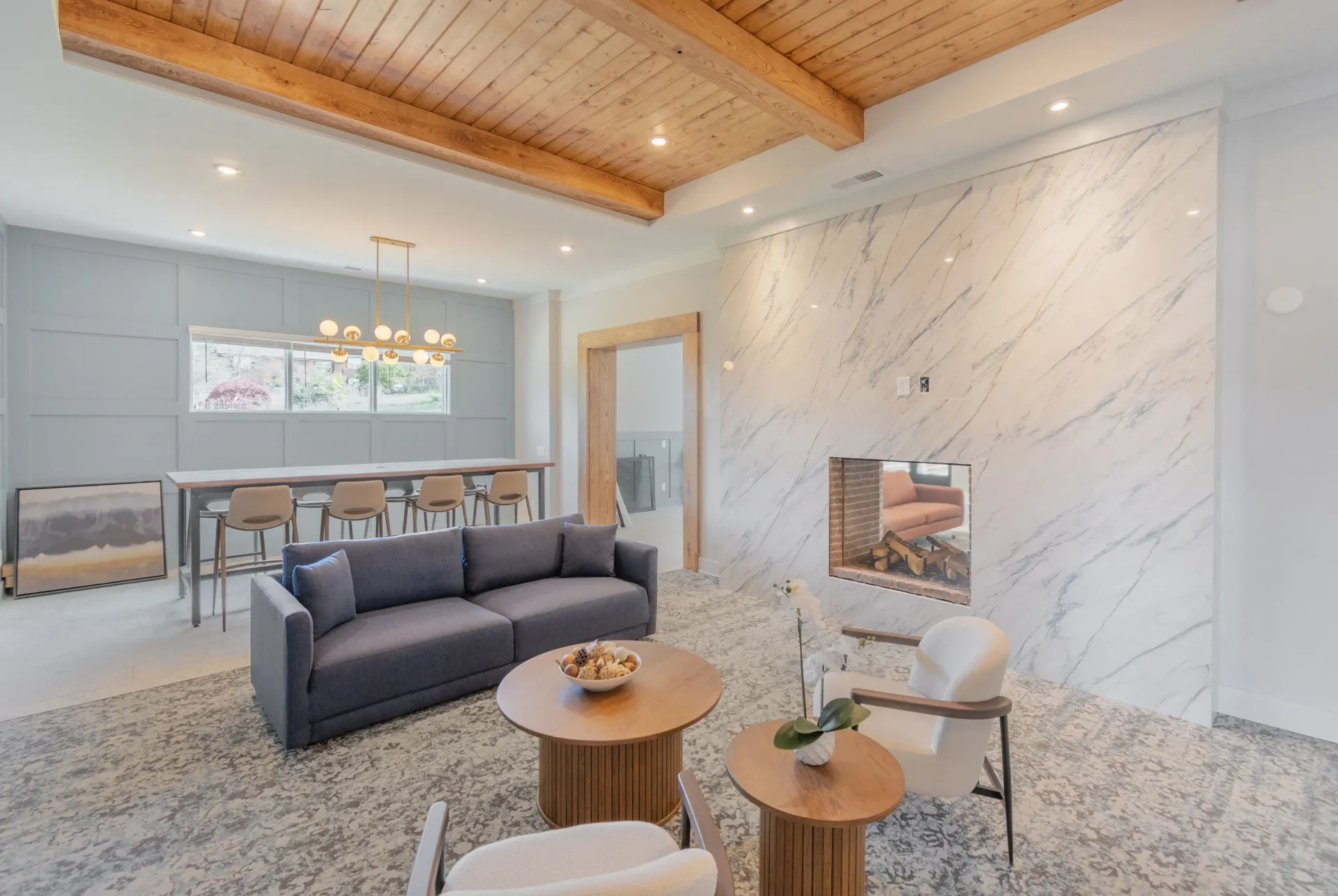 Modern lounge area with a large dark sofa, coffee tables, and a marble fireplace.