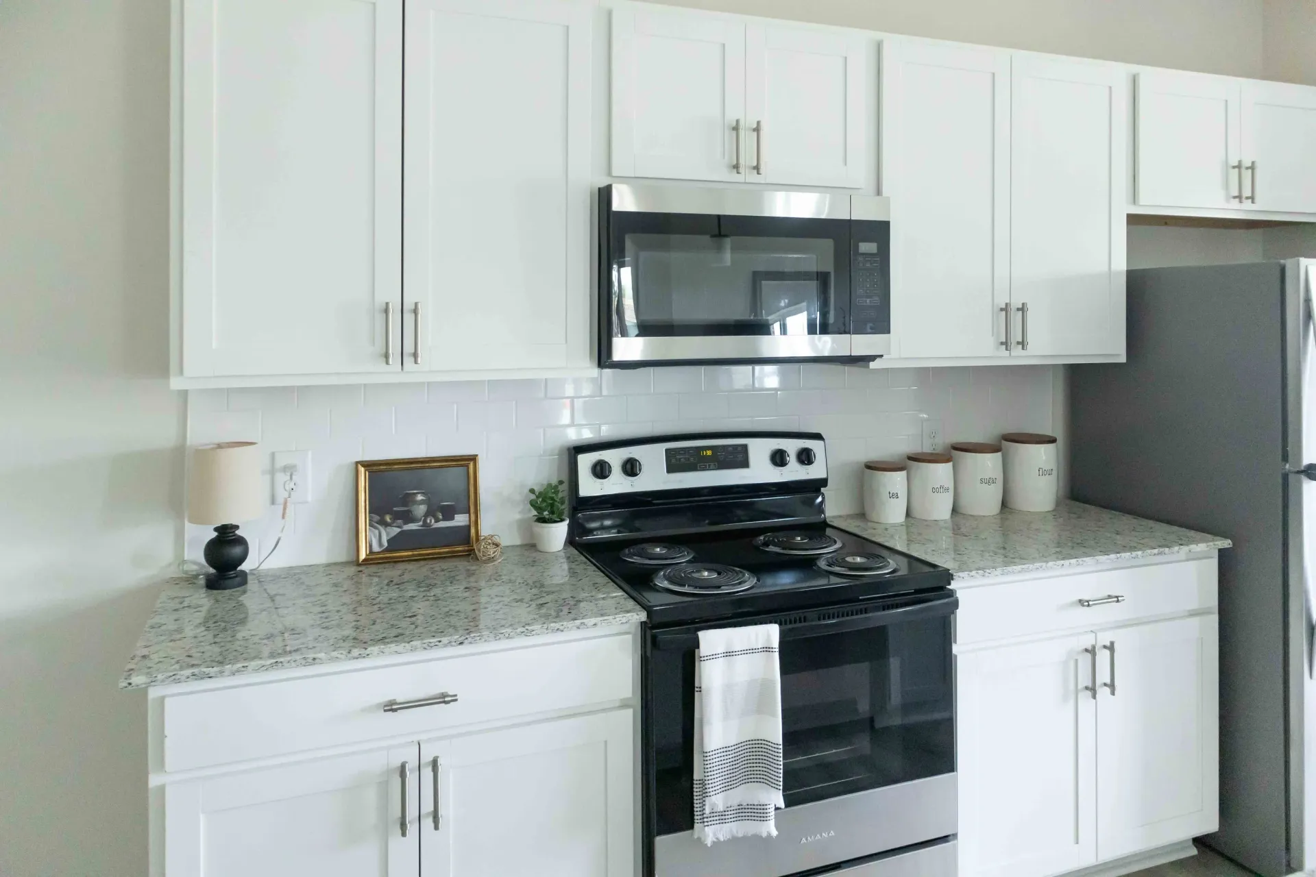 Modern kitchen with white cabinets, granite countertops, and stainless steel appliances.
