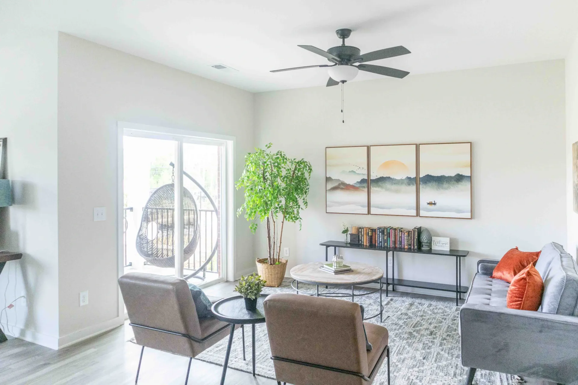 Living room with a hanging chair, two armchairs, a sofa, and wall art.