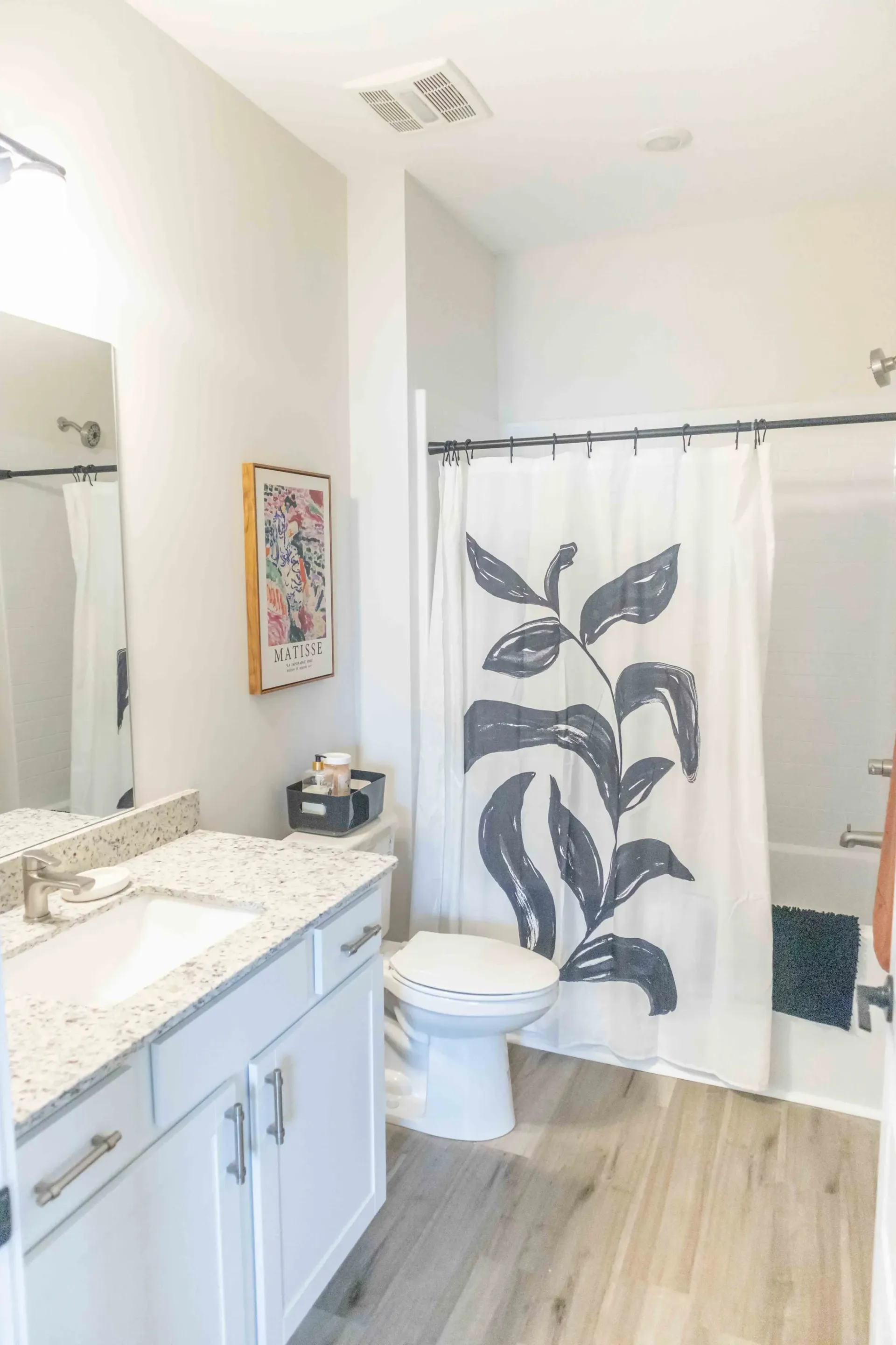 Modern bathroom with vanity, toilet, and shower with floral print curtain.