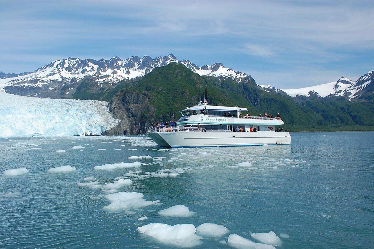 Cruise ship near a glacier and snowcapped mountains on a calm blue sea