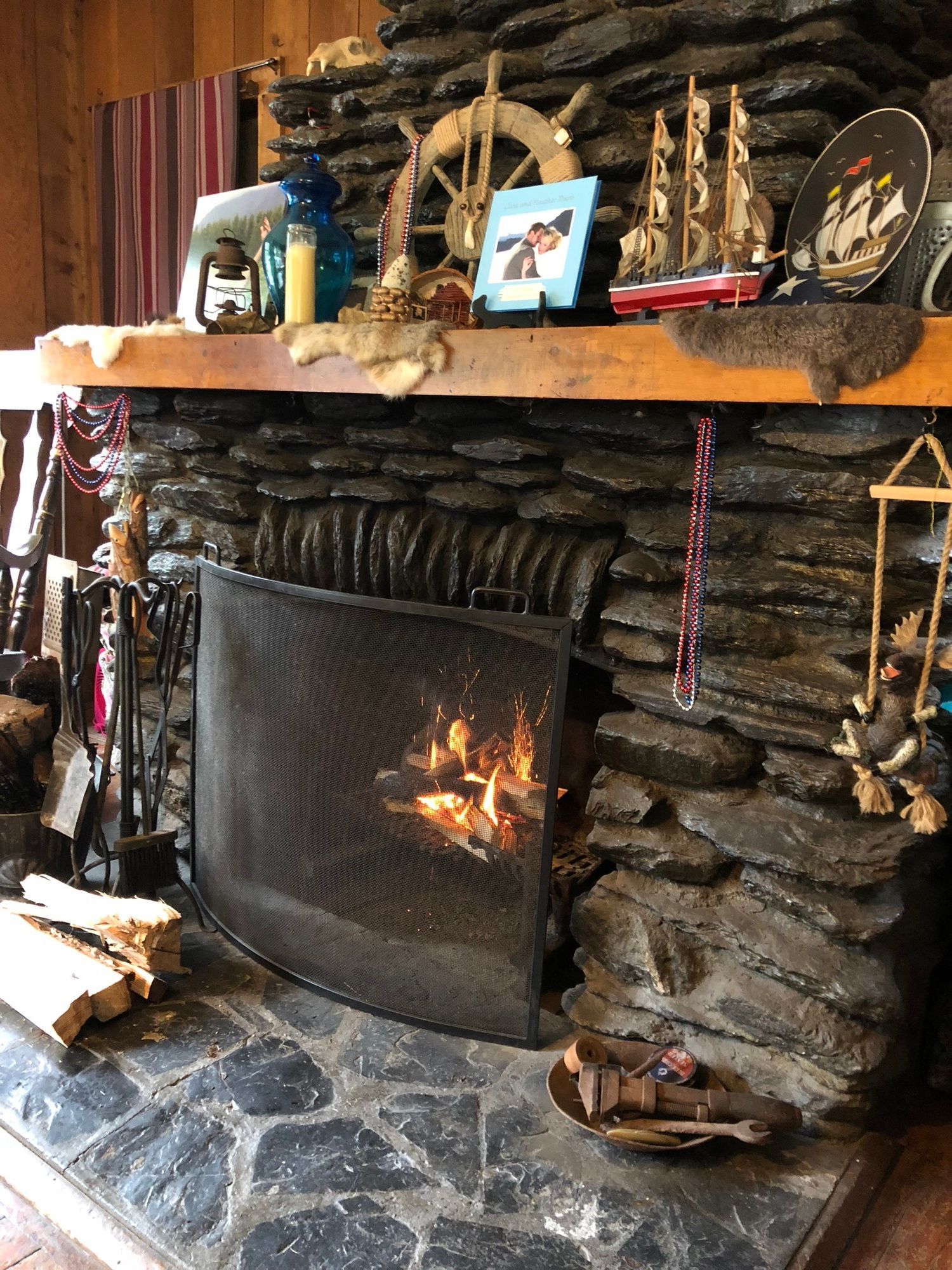 Stone fireplace with burning fire and nautical-themed decorations on a wooden mantel.