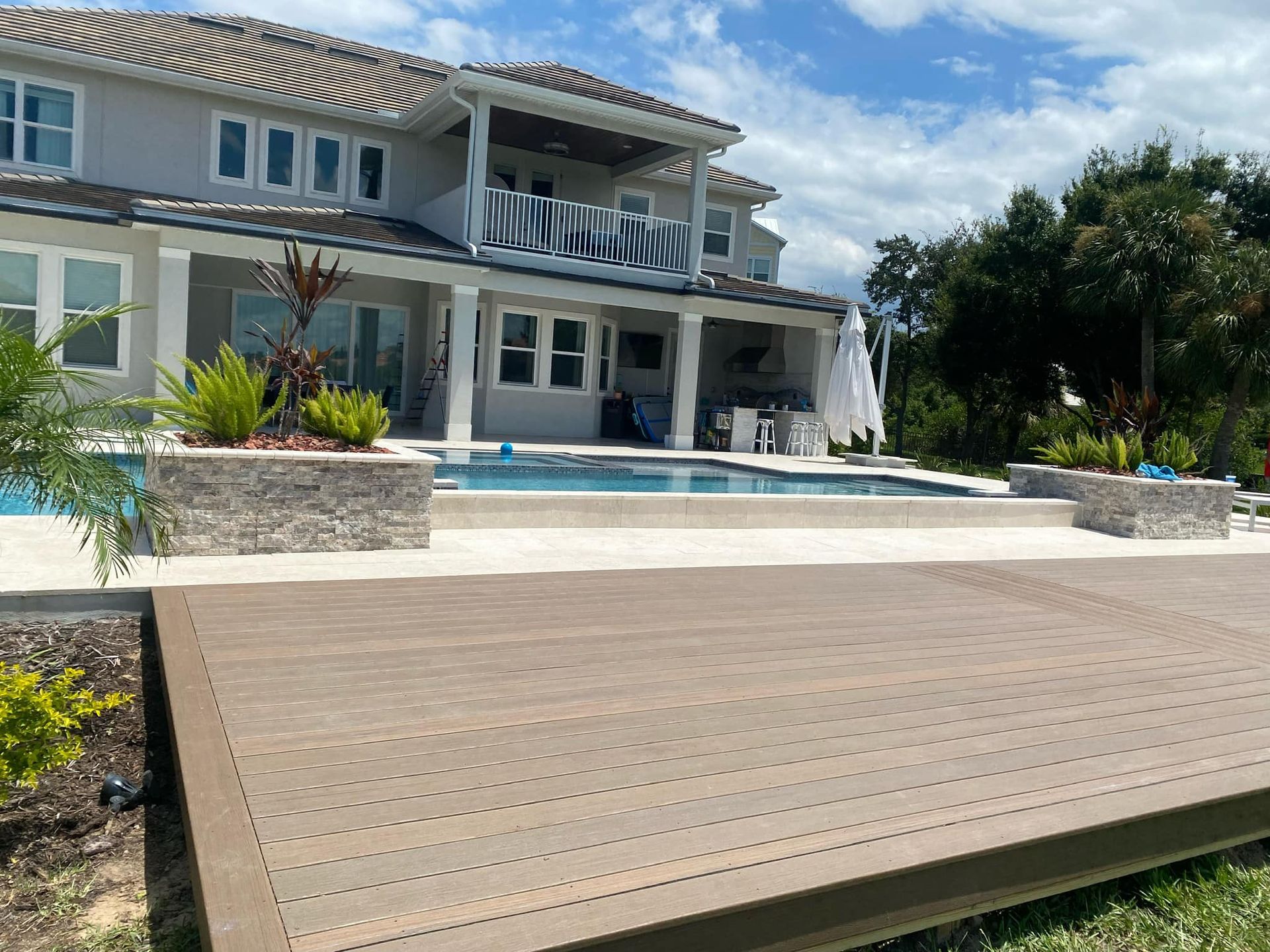 A large house with a swimming pool and a wooden deck in front of it.