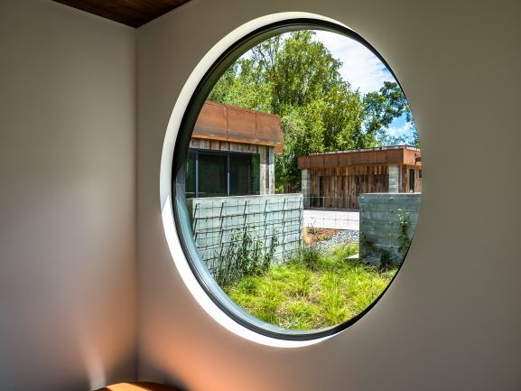 There is a round window in the corner of a room.