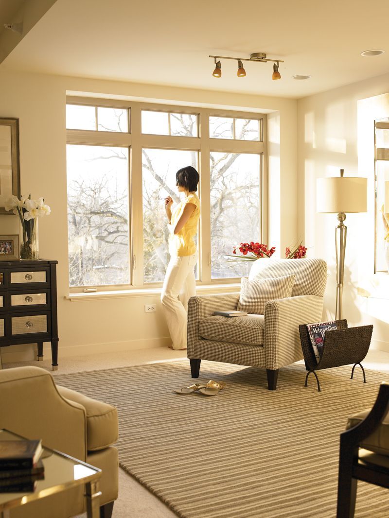 A woman stands in a living room looking out a window