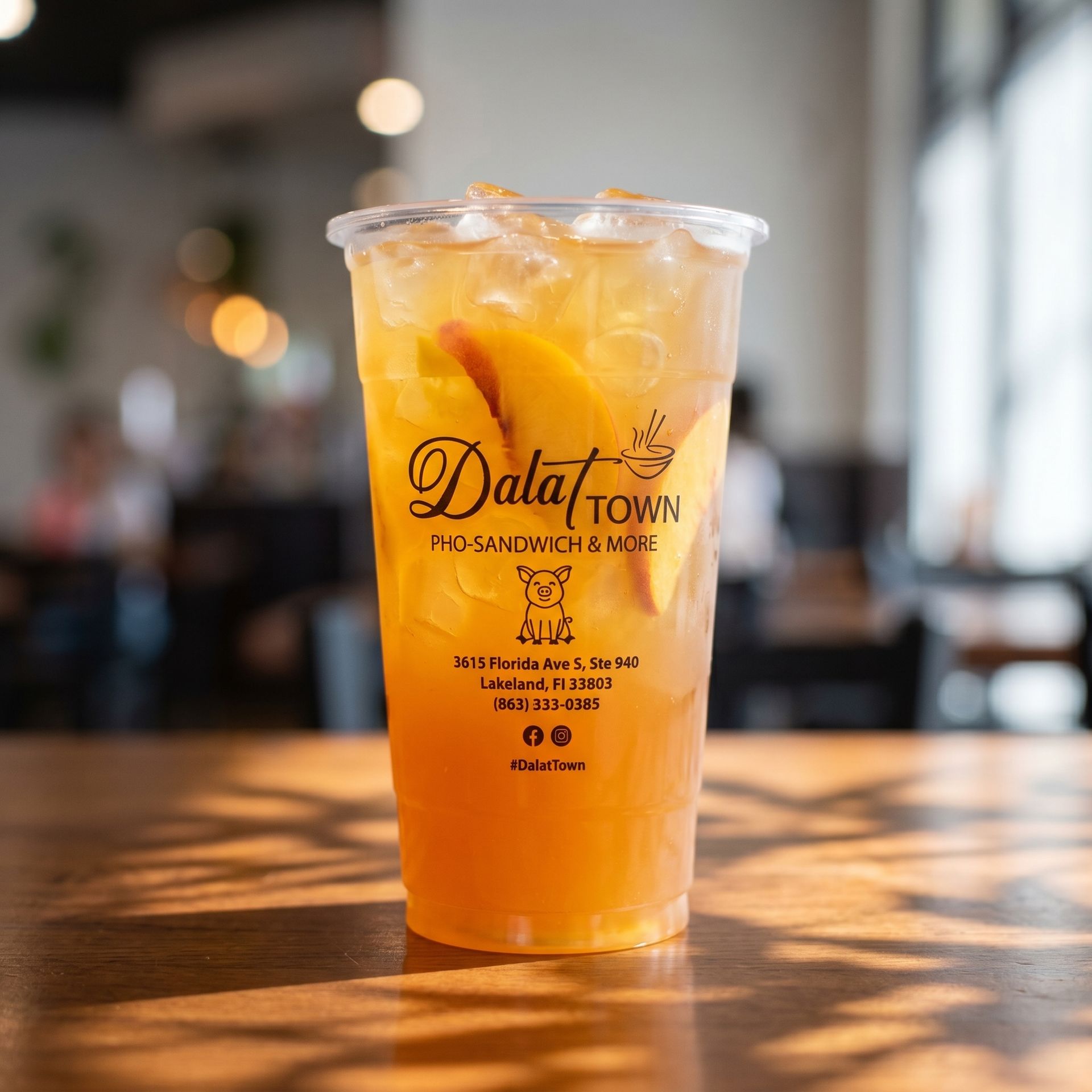 Clear cup of orange iced drink on a wooden table in a blurred café