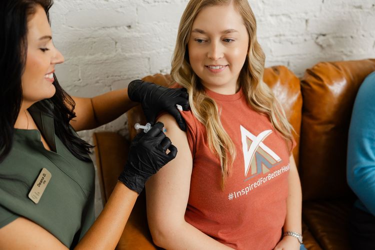 Woman receiving a shoulder injection from a nurse on a couch