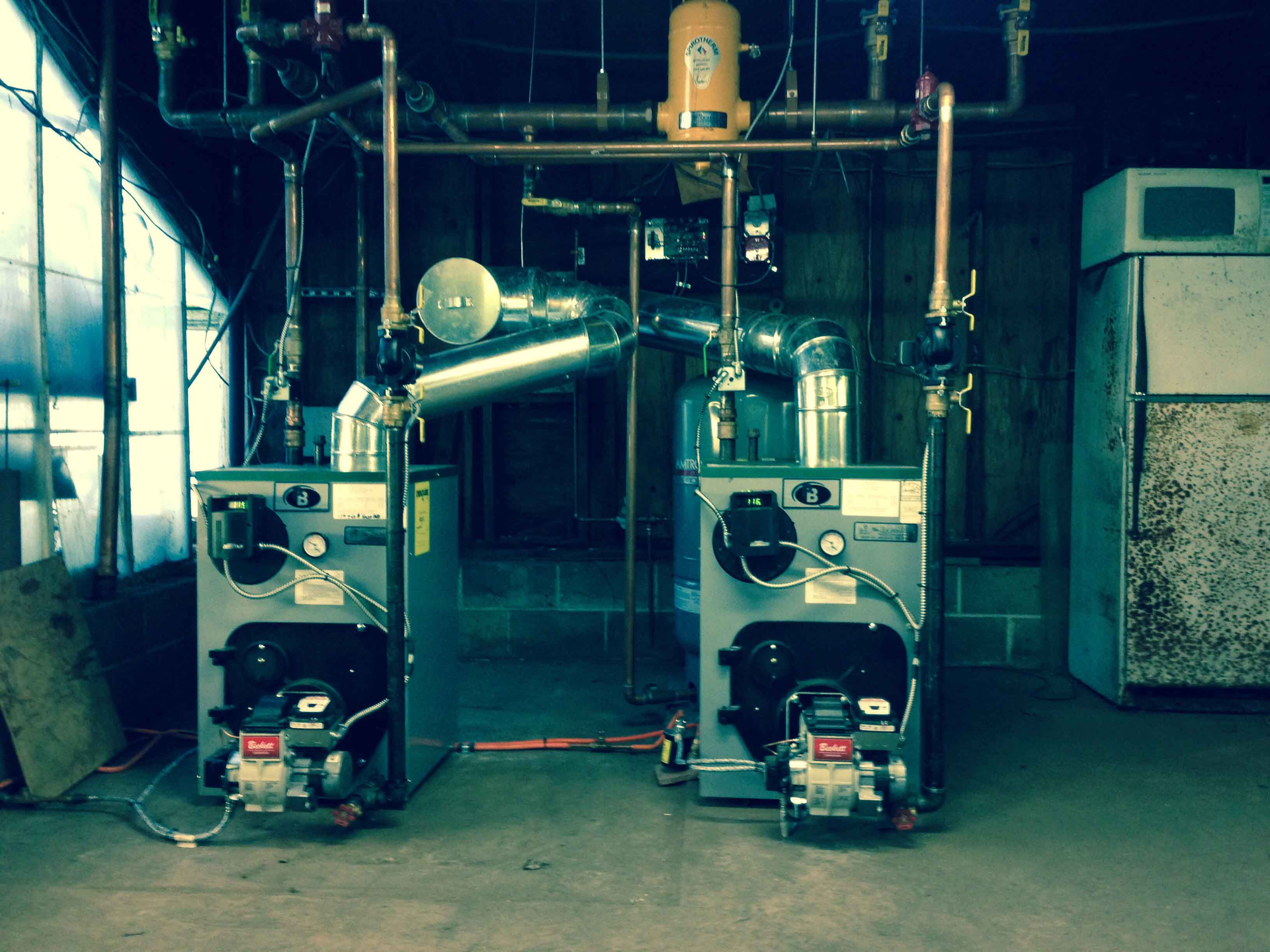 Two industrial machines with pipes and gauges in a workshop room