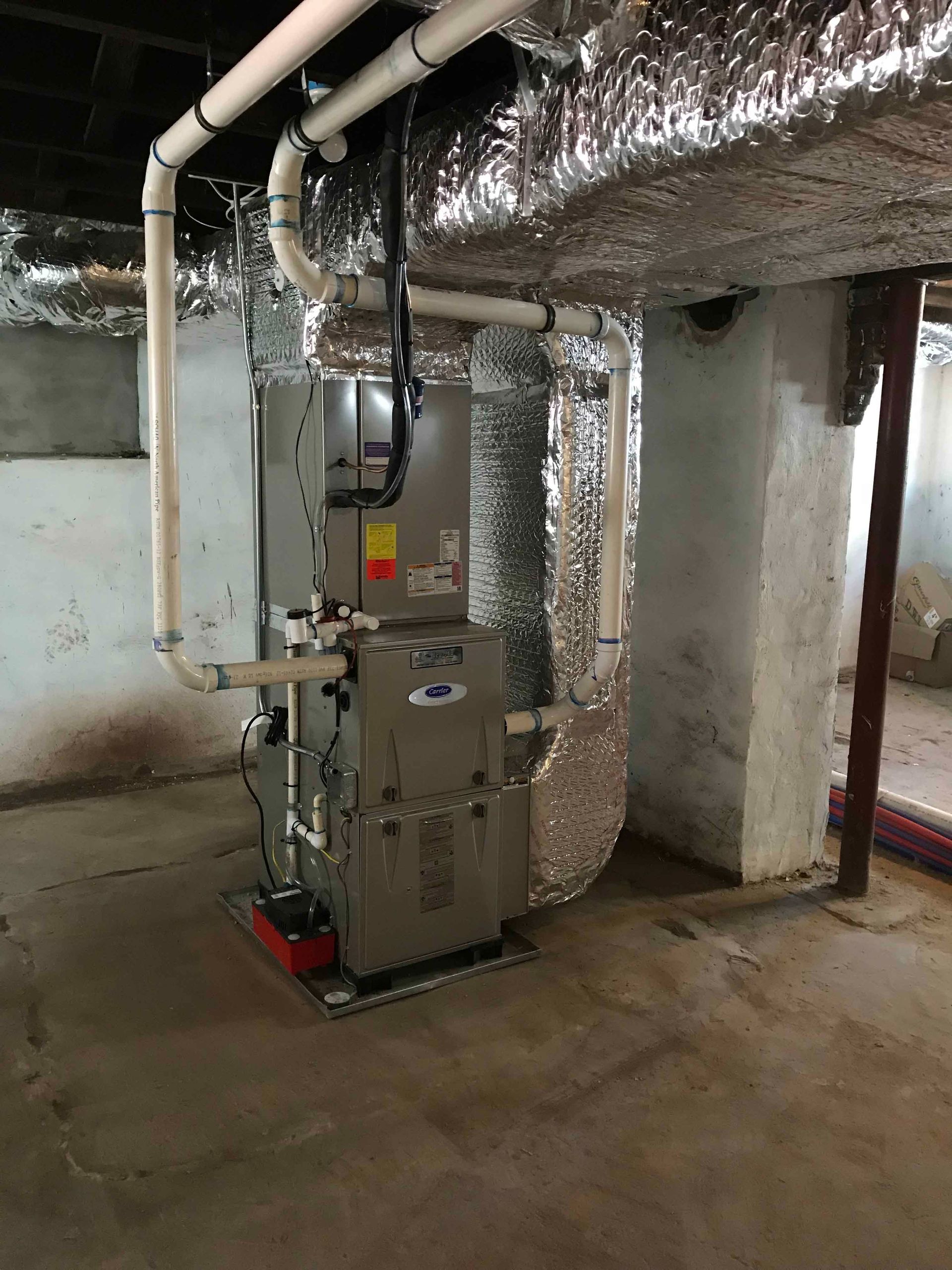 Basement furnace and ductwork wrapped in silver insulation in a utility room
