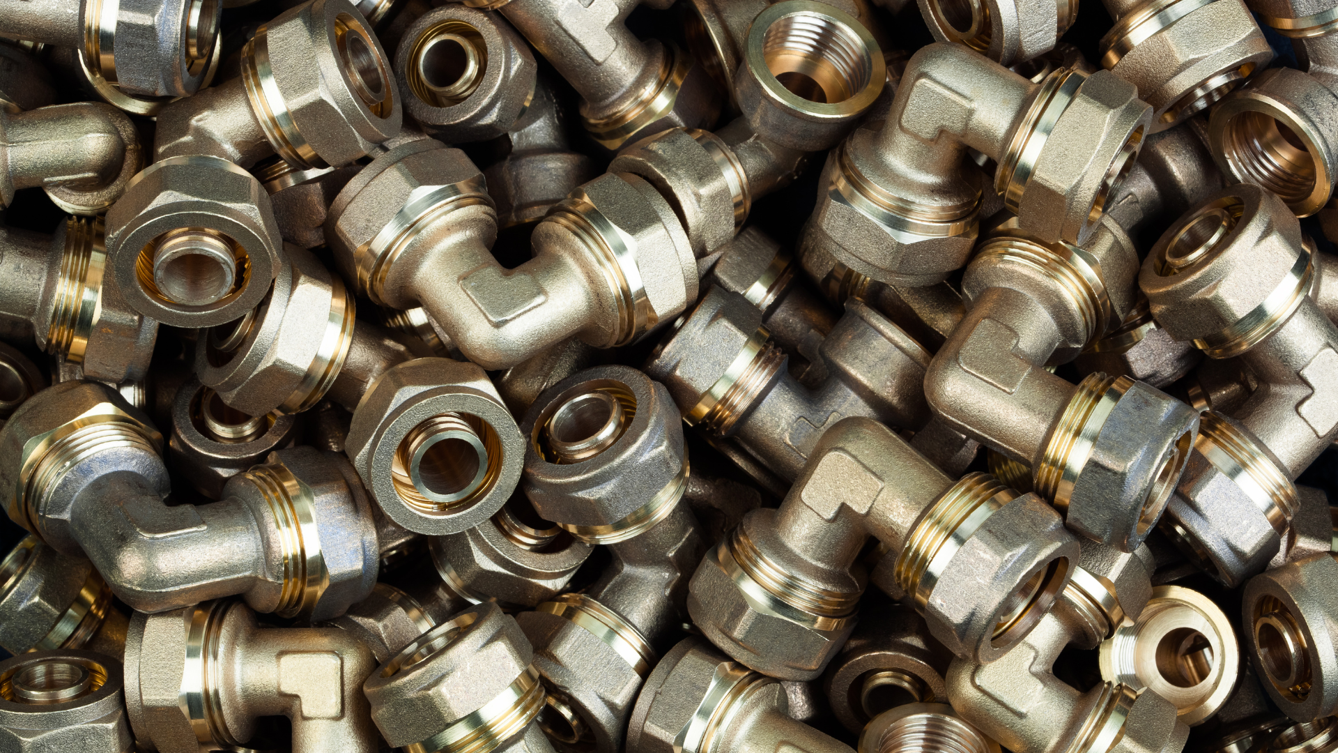 Pile of shiny metal pipe fittings stacked tightly together