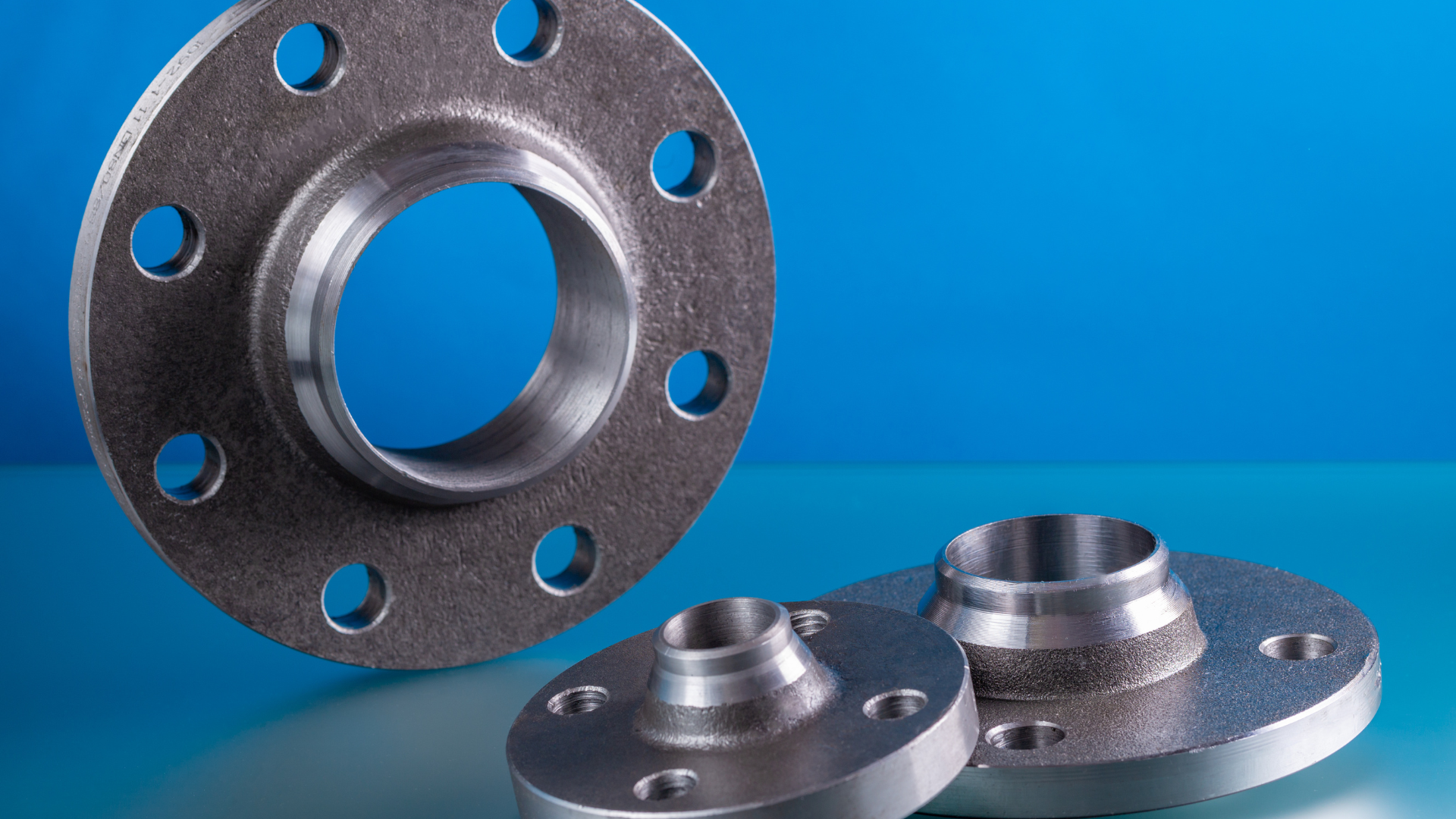 Metal flanges with bolt holes on a blue background