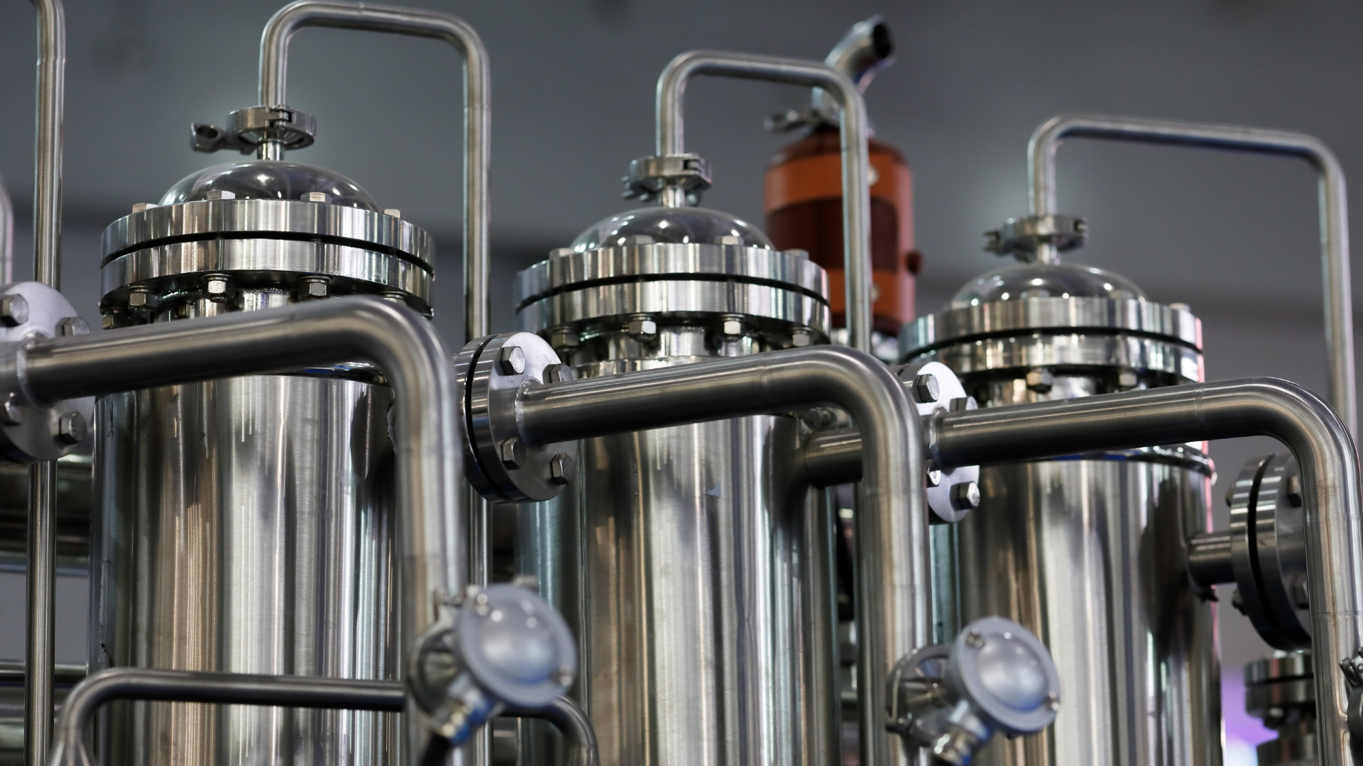 Stainless steel industrial processing tanks with pipes and gauges in a factory setting