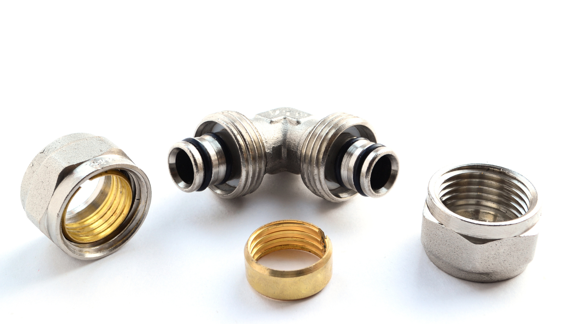 Assorted metal pipe fittings and connectors on a white background, including silver and brass pieces.