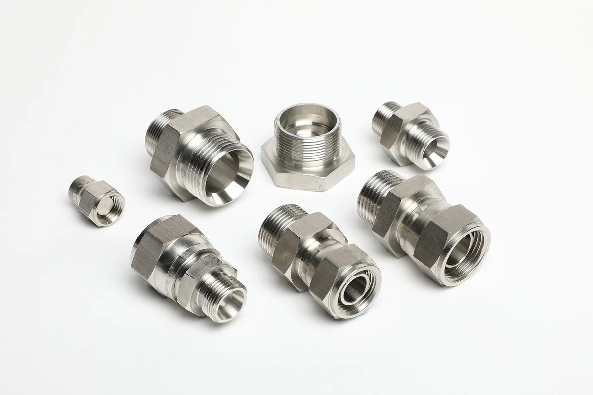 Assorted silver metal cable glands and fittings arranged on a white background