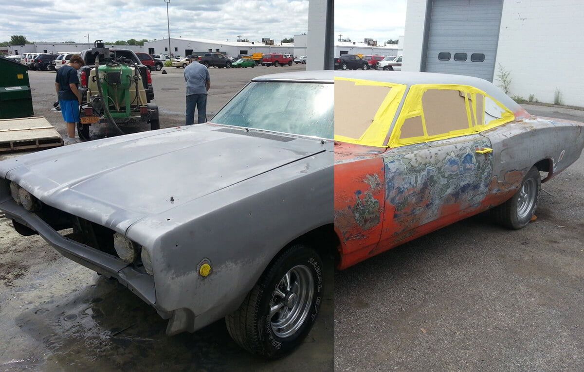 A dodge charger is sitting in a parking lot next to a tractor.